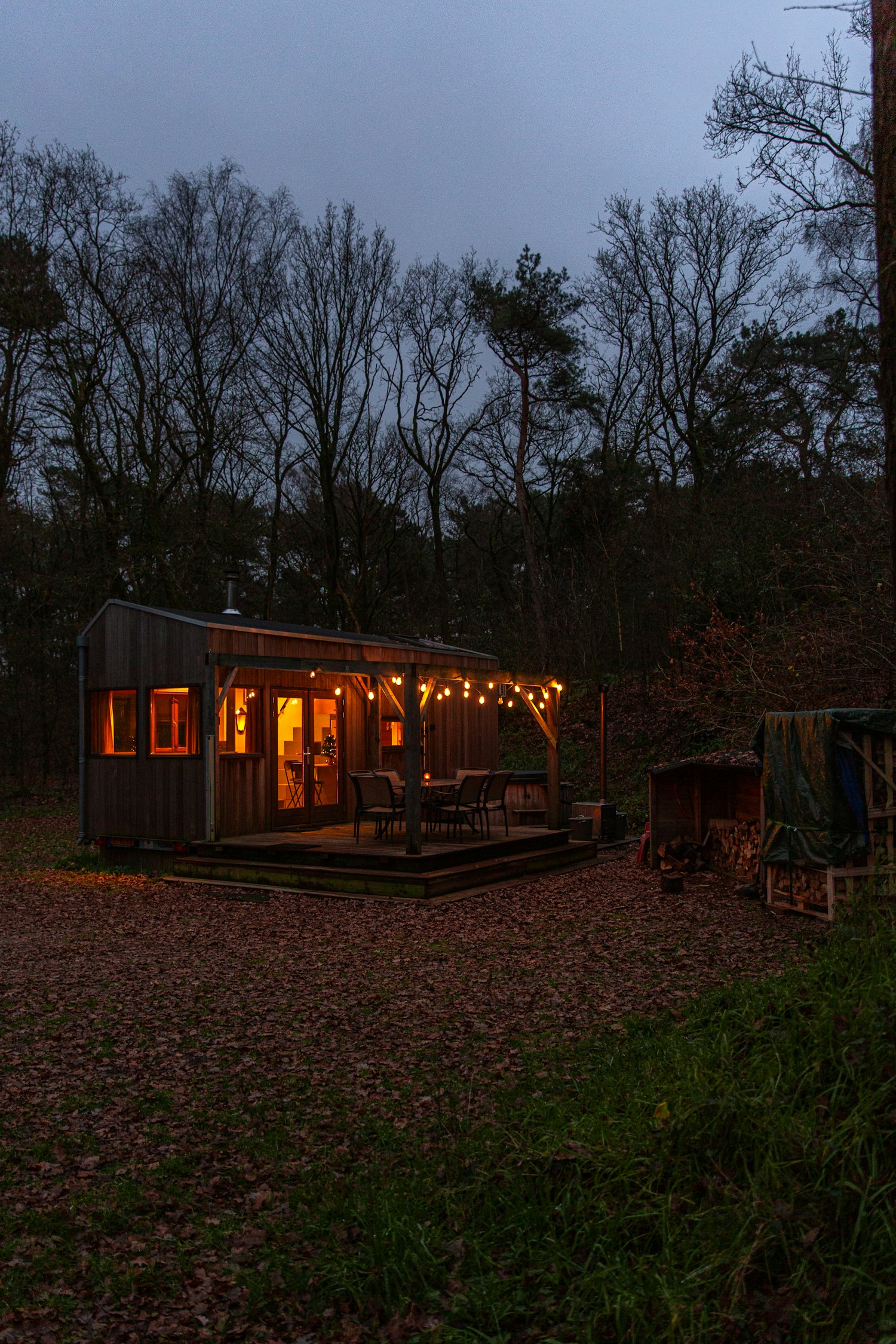 The Roost, a festoon-lit family timber cabin at dusk